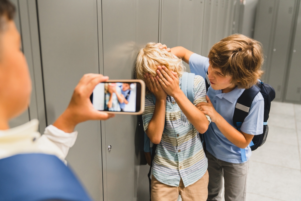 bambino bullizzato mentre un compagno riprende la scena con lo smartphone